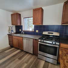 Kitchen with decorative backsplash, appliances with stainless steel finishes, dark hardwood / wood-style floors, and sink