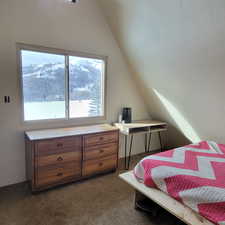 Bedroom with a mountain view, vaulted ceiling, and dark carpet