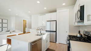 Kitchen featuring white cabinets, stainless steel appliances, a kitchen island with sink