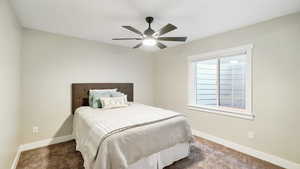 Bedroom with dark colored carpet and ceiling fan