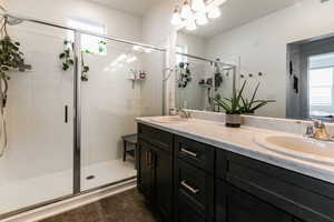 Bathroom with vanity, a shower with shower door, and a notable chandelier