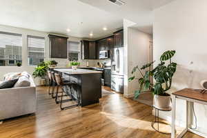 Kitchen featuring a center island, a breakfast bar area, dark brown cabinets, light hardwood / wood-style floors, and stainless steel appliances