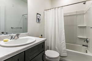 Full bathroom featuring vanity, shower / bathtub combination with curtain, and toilet