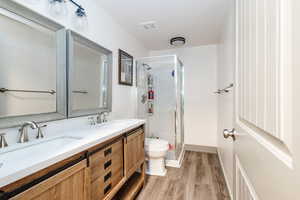 Bathroom featuring walk in shower, toilet, vanity, and hardwood / wood-style flooring