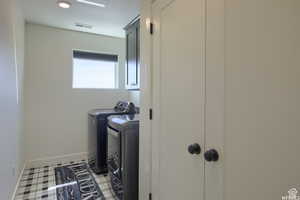 Washroom with tile patterned flooring, cabinets, and washing machine and dryer