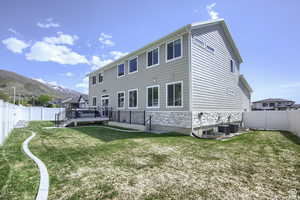 Back of property featuring a deck with mountain view, a yard, and central AC