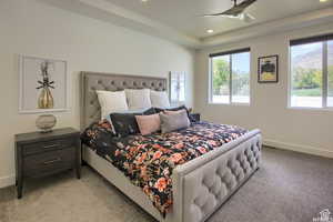 Bedroom featuring light colored carpet and ceiling fan.  Windows offer natural light