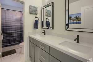 Bathroom featuring tile patterned flooring, vanity, toilet, and a shower with shower curtain