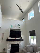 Living room featuring a fireplace, high vaulted ceiling, and a healthy amount of sunlight