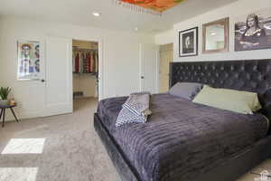 Carpeted bedroom with a walk in closet lots of natural light