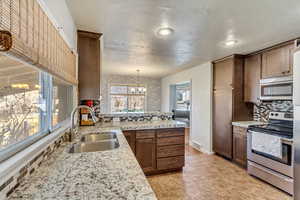 Kitchen with sink, decorative backsplash, appliances with stainless steel finishes, decorative light fixtures, and a chandelier