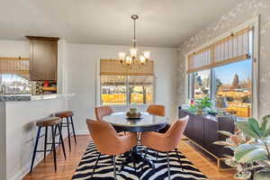 Dining room with an inviting chandelier, a healthy amount of sunlight, and light wood-type flooring