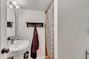 Bathroom featuring sink, a textured ceiling, and walk in shower