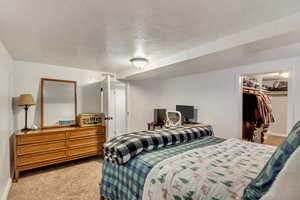 Carpeted bedroom featuring a walk in closet, a textured ceiling, and a closet