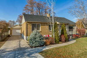 View of front of property with a front yard, a garage, and an outdoor structure