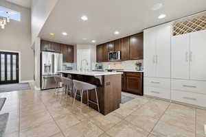 Kitchen featuring a kitchen bar, an island with sink, light tile patterned floors, and appliances with stainless steel finishes