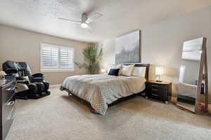 Carpeted bedroom featuring a textured ceiling and ceiling fan