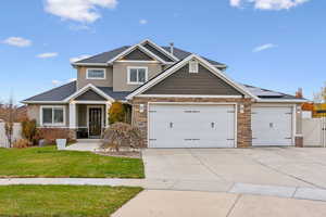 Craftsman inspired home featuring solar panels, a garage, and a front yard