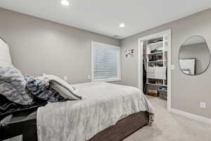 Bedroom with a spacious closet and light carpet