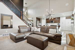 Tiled living room featuring a fireplace, a towering ceiling, and an inviting chandelier