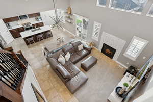 Living room with plenty of natural light, a towering ceiling, and a tile fireplace