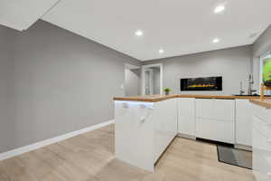 Kitchen featuring kitchen peninsula, white cabinetry, sink, and light hardwood / wood-style floors