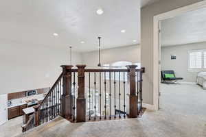 Corridor with a textured ceiling, light colored carpet, and plenty of natural light