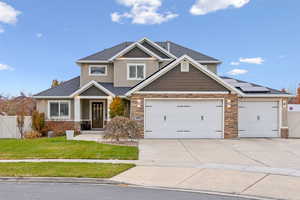 Craftsman inspired home with a front lawn, a garage, and solar panels