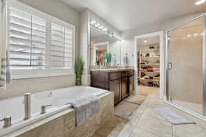 Bathroom featuring tile patterned floors, plus walk in shower, and vanity