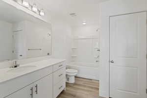 Full bathroom featuring hardwood / wood-style floors, vanity, toilet, and shower / bath combination