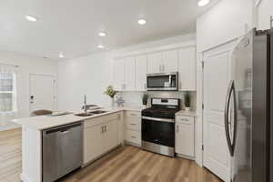 Kitchen with sink, tasteful backsplash, light hardwood / wood-style flooring, kitchen peninsula, and appliances with stainless steel finishes