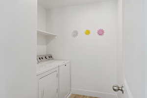 Clothes washing area with washer and dryer and light wood-type flooring