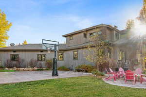 Rear view of house featuring basketball court and a lawn