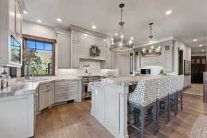 Kitchen with sink, a center island, high end stainless steel range oven, dark hardwood / wood-style floors, and decorative light fixtures