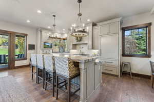 Kitchen with light stone countertops, a kitchen breakfast bar, decorative light fixtures, dark hardwood / wood-style floors, and a kitchen island