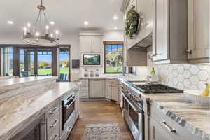 Kitchen with decorative backsplash, light stone countertops, dark wood-type flooring, and stainless steel appliances