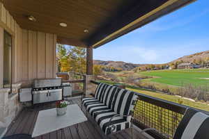 Wooden deck with a mountain view, area for grilling, and an outdoor living space