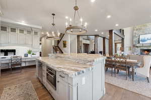 Kitchen with white cabinetry, a center island, decorative light fixtures, a fireplace, and hardwood / wood-style flooring