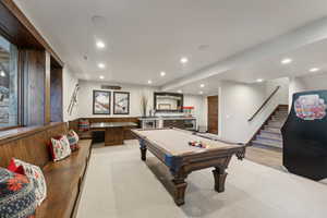 Recreation room featuring light colored carpet, bar, wood walls, and billiards