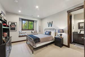 Bedroom with light hardwood / wood-style flooring and ensuite bath