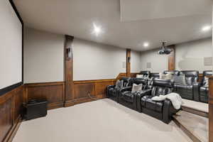 Home theater room with carpet and wooden walls