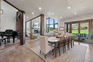 Dining space featuring a fireplace, high vaulted ceiling, and light hardwood / wood-style floors