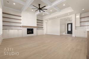 Unfurnished living room featuring ceiling fan with notable chandelier, light hardwood / wood-style floors, ornamental molding, and beam ceiling