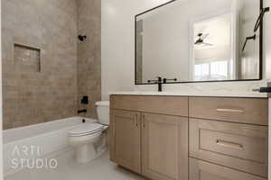 Full bathroom featuring tile patterned floors, vanity, tiled shower / bath combo, ceiling fan, and toilet