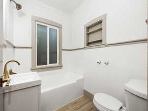 Bathroom with a bathtub, crown molding, wood-type flooring, tile walls, and toilet