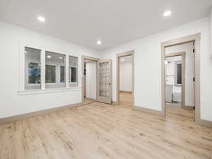 Unfurnished bedroom with light wood-type flooring, french doors, and ensuite bath