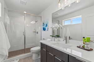 Bathroom featuring toilet, walk in shower, tile patterned floors, and vanity