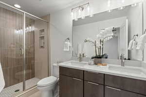 Bathroom with a shower with shower door, toilet, and vanity