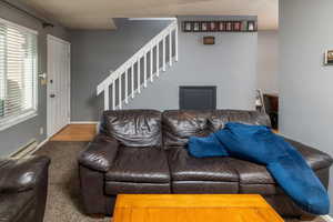 Carpeted living room with baseboard heating and a textured ceiling