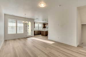 Unfurnished living room with a chandelier and light wood-type flooring